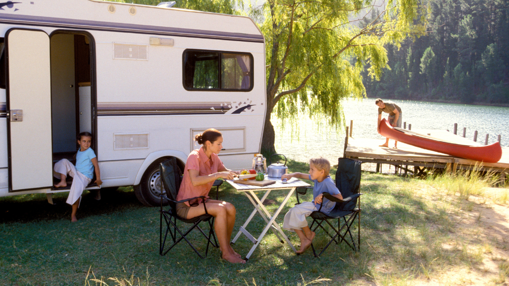 A family enjoying their camping trip in front of their trailer.
