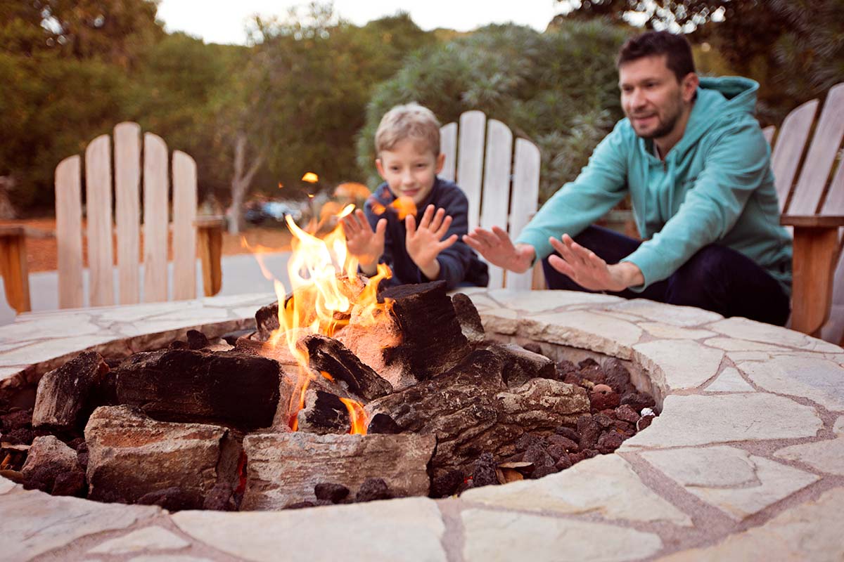 Family warming their hands by an outdoor propane fire pit.