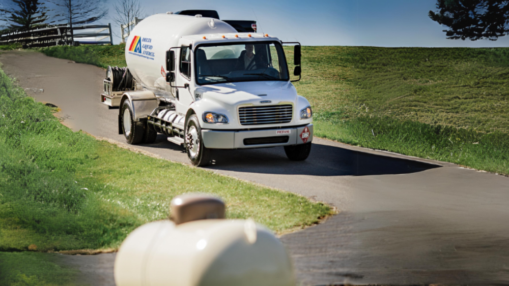 Propane bobtail driving down road with propane tank in the forefront